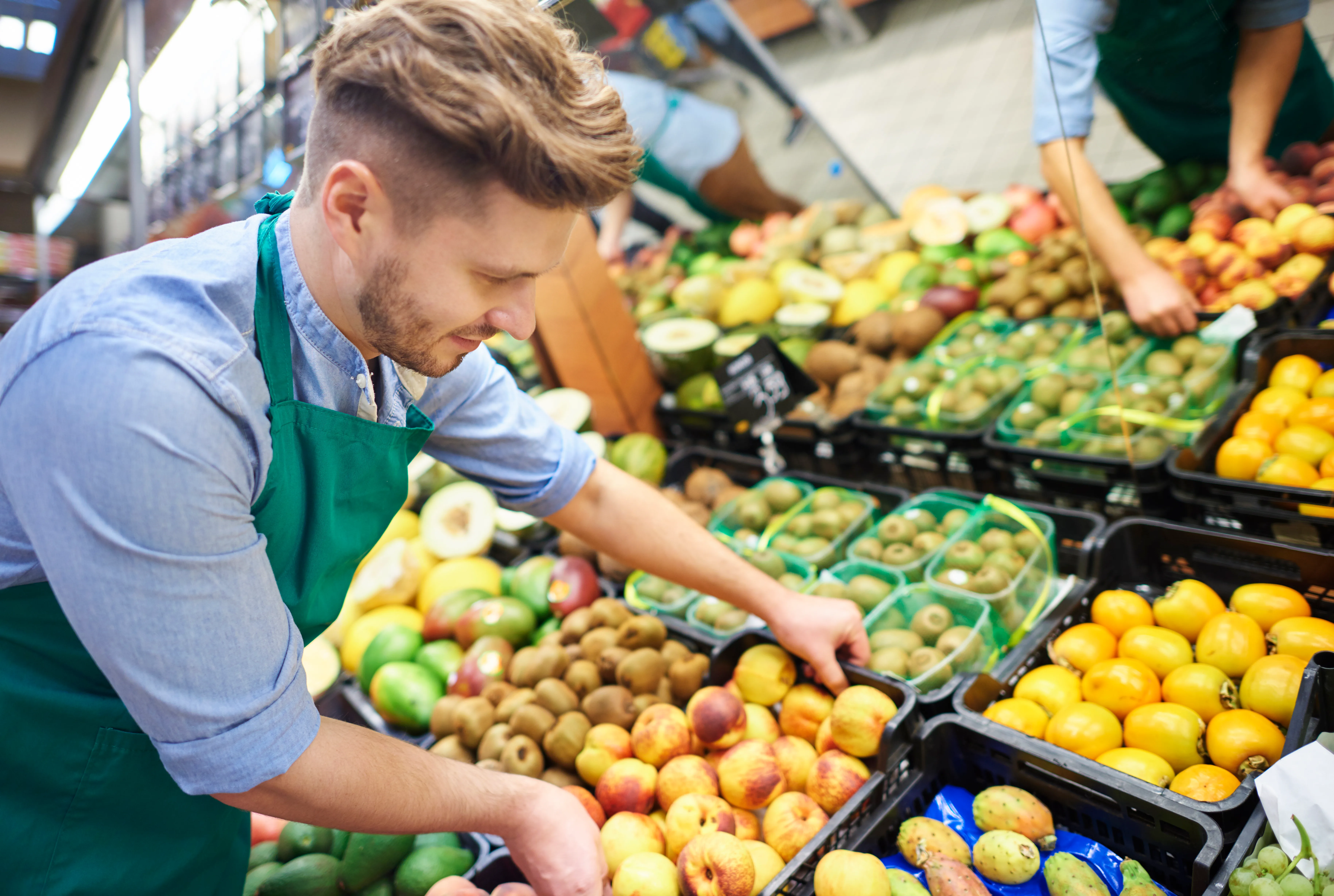 Grocer arranging a fresh produce display at a wholesale market
